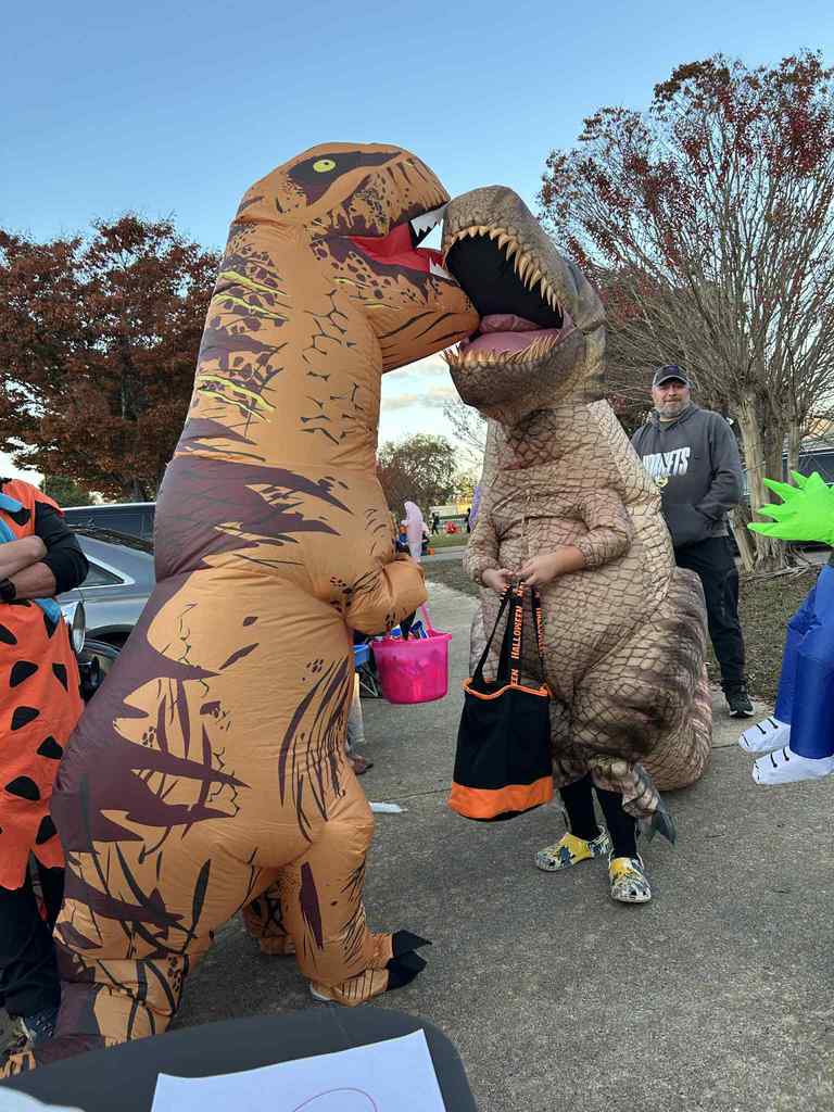 Two Kids dressed as dinosaurs trunk or treating