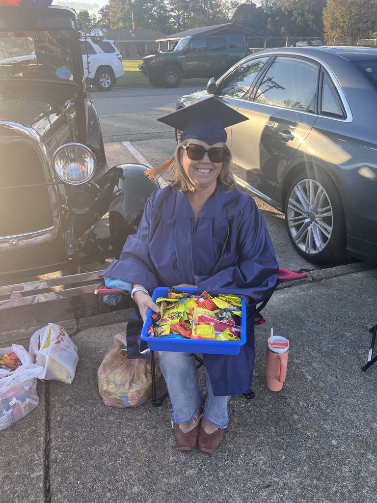 A teacher dressed as a graduate trunk or treating