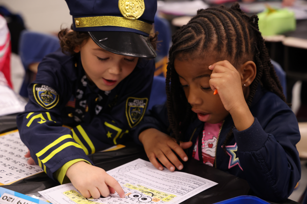 boy dressed a spolice officer helping a gril with math