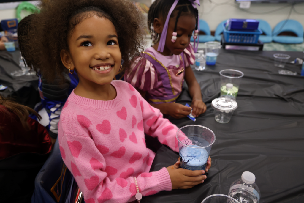 little girl smiling with her cup of fizzing blue concoction