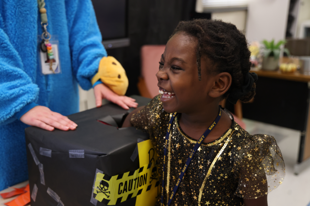 little girl smiling and reaching into box