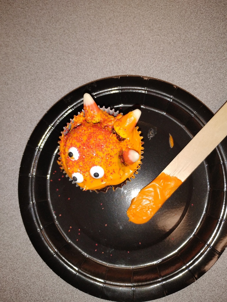 Cupcake montster with orange icing, decorated with candy corn and candy eyeballs