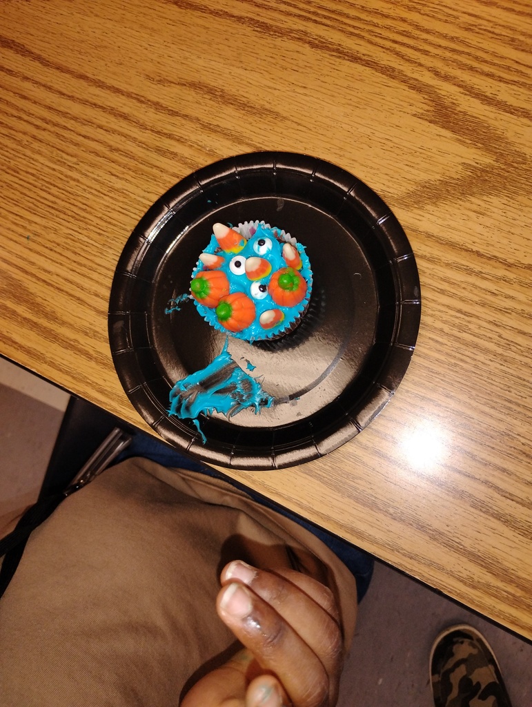 Cupcake montster with blue icing, decorated with candy pumpkins, candy corn, and candy eyeballs