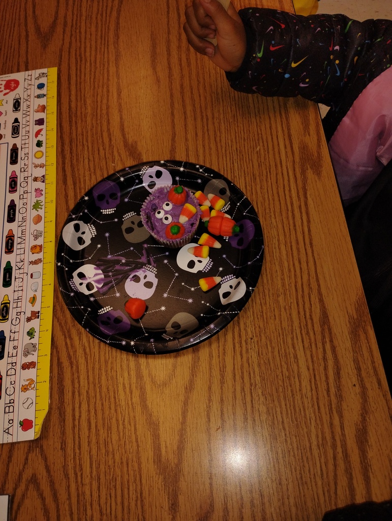 Cupcake montster with purple icing, decorated with candy pumpkins, candy corn, and candy eyballs