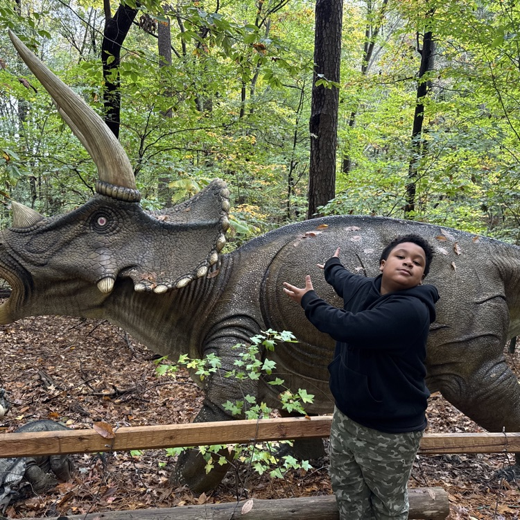 student by statue of a dinosaur 
