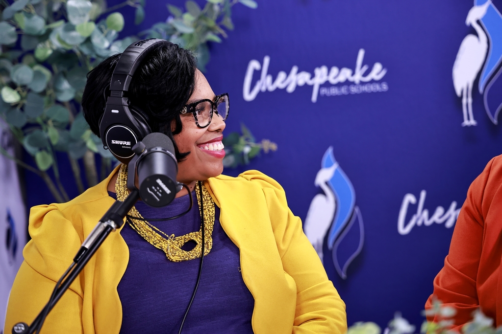Lisa smiling in the studio with a headset and mic.
