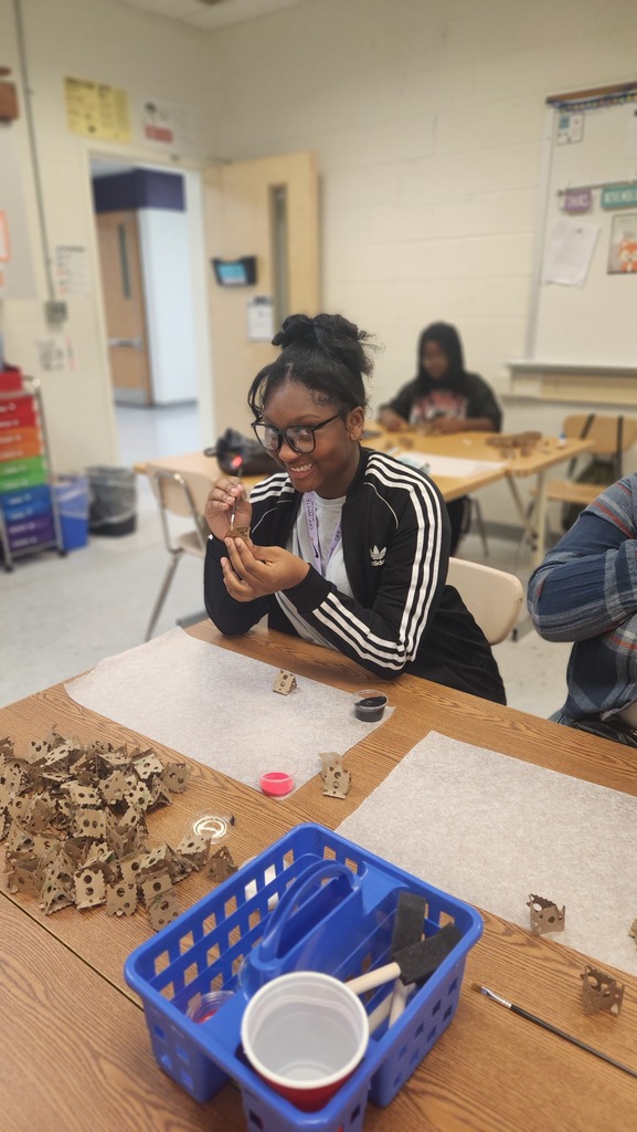 a student making bracelet and smiling at the bracelet making club