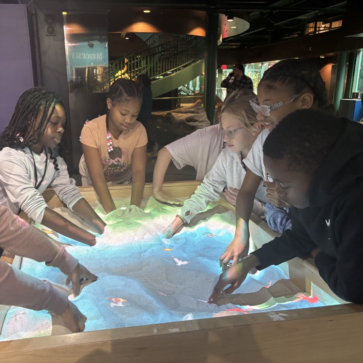 student around touch sand table with projector 