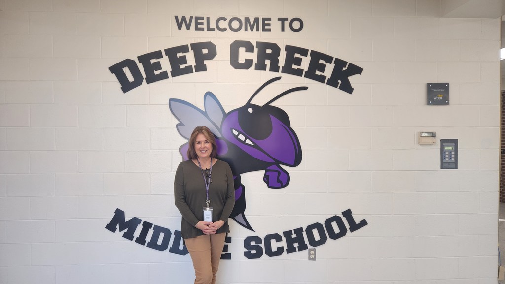 Mrs. Heine in front of our Welcome to Deep Creek Middle School sign