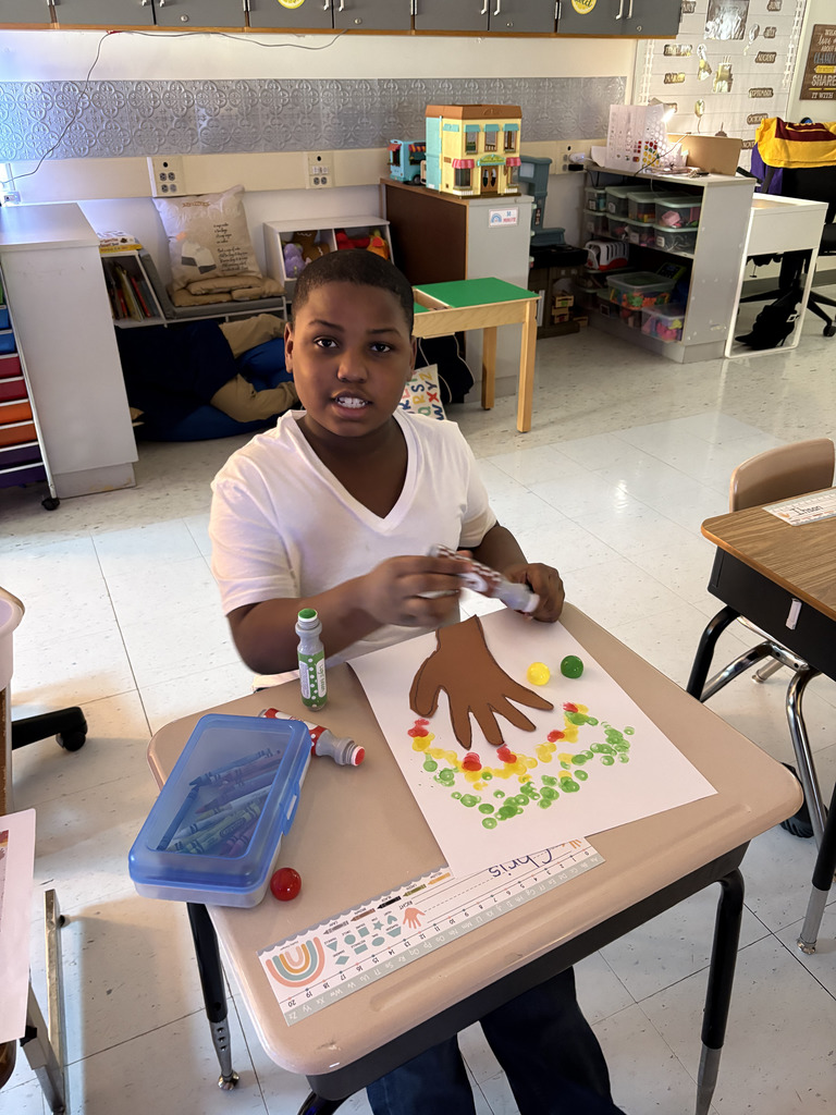 students creating colorful fall trees with hand trunks and bingo marker leaves