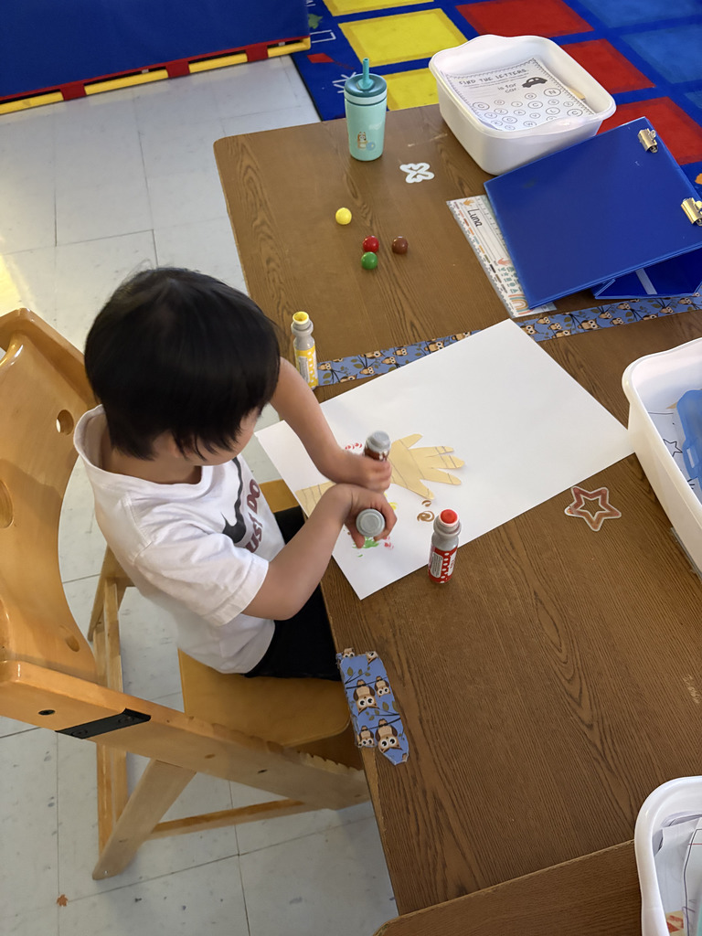 students creating colorful fall trees with hand trunks and bingo marker leaves