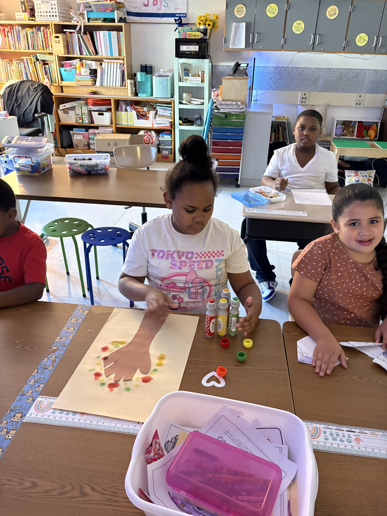 students creating colorful fall trees with hand trunks and bingo marker leaves