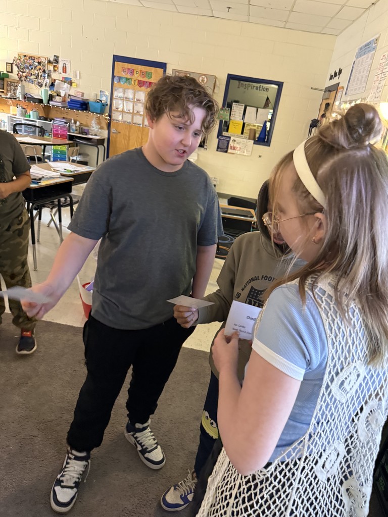 Students bartering with each other-holding cards and talking in a circle