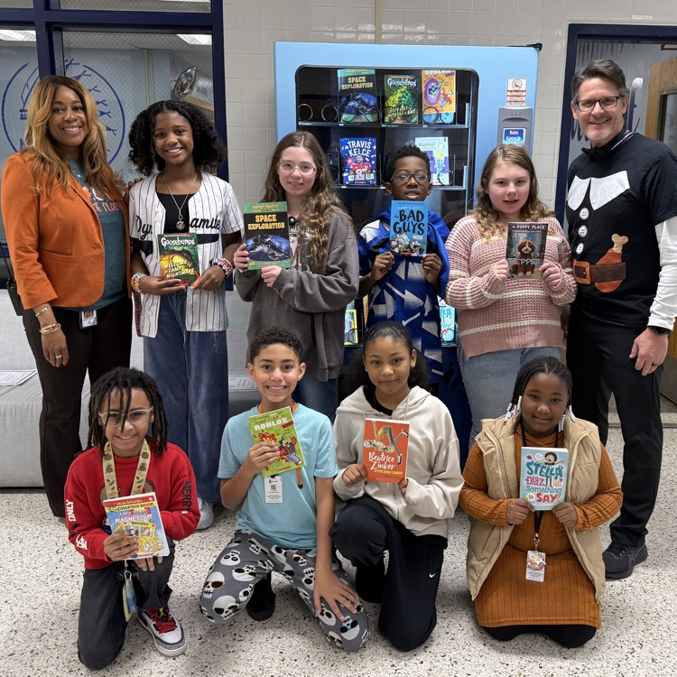 5th grade Junior Braves of the month with admin in front of book vending machine holding up books