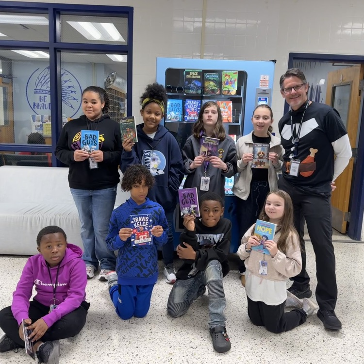 4th grade Junior Braves of the month with admin in front of book vending machine holding up books