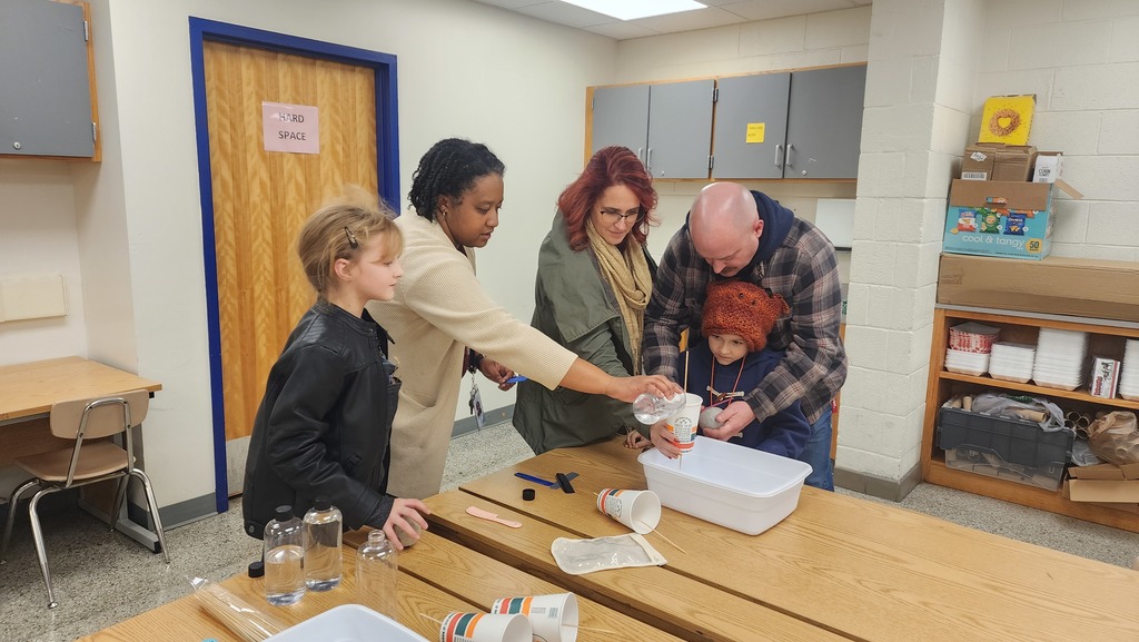 Family and teacher using a comb (static electricity) to move water flowing through a cup.