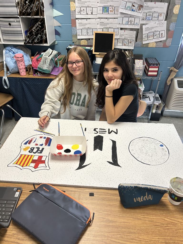 two girls paining soccer clubs on ceiling tiles