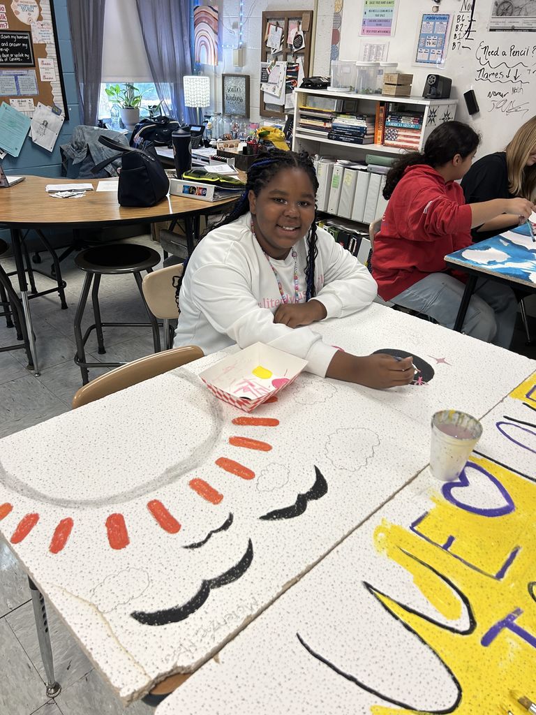 A student painting tiles. With a sun