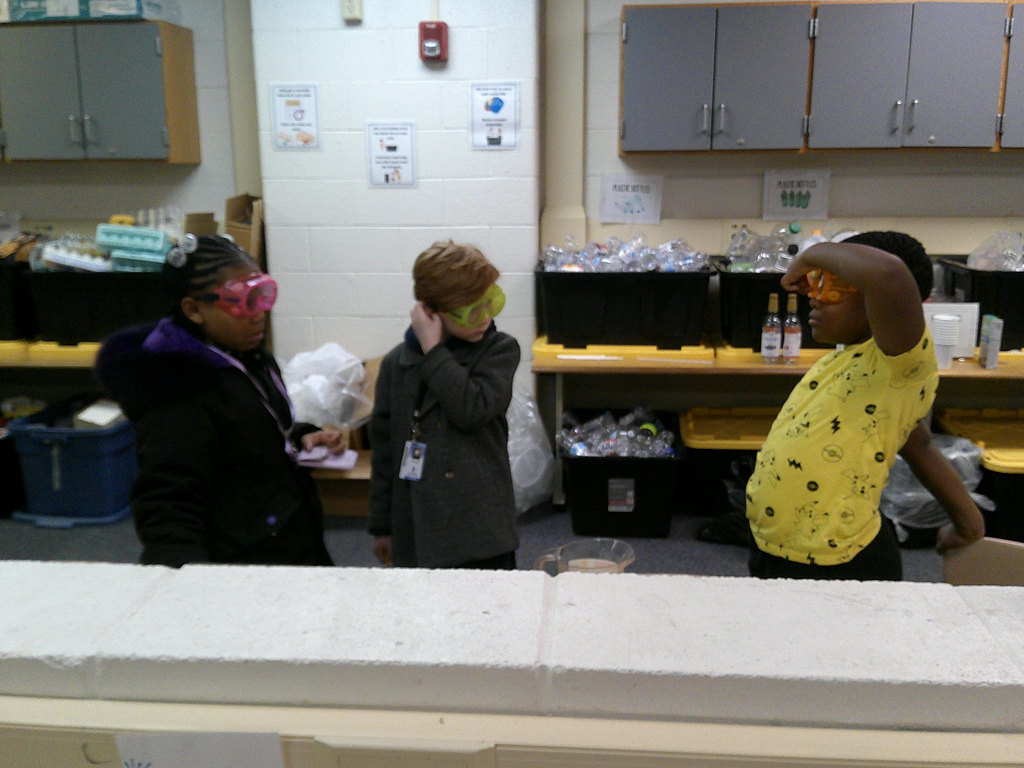 students practicing safety by putting on their goggles before starting their experiment