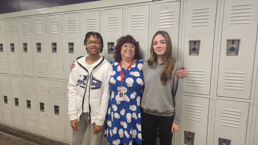 A teacher and two students wearing a white, blue, and gray