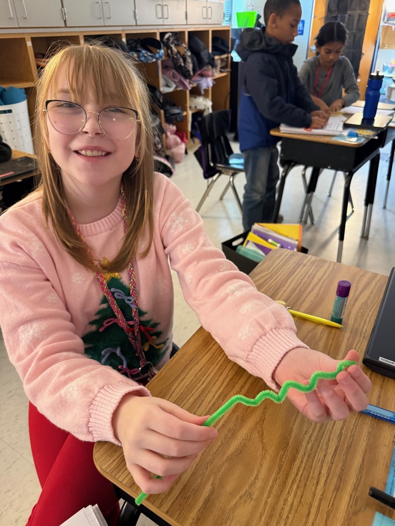 Student holding up green pipe cleaner for light