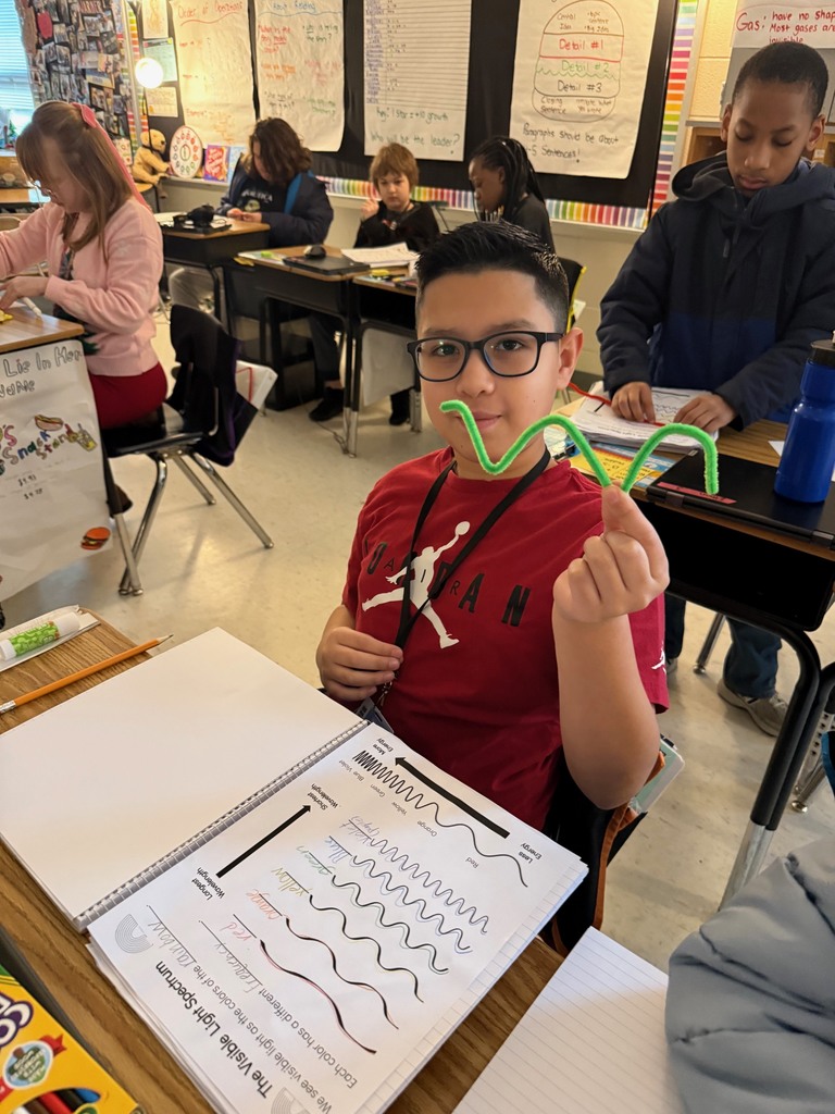 Student holding up green pipe cleaner for light