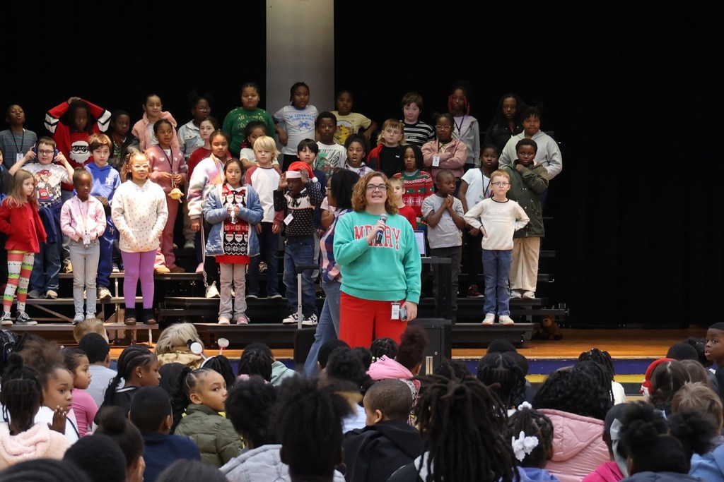 principal giving speech in front of risers