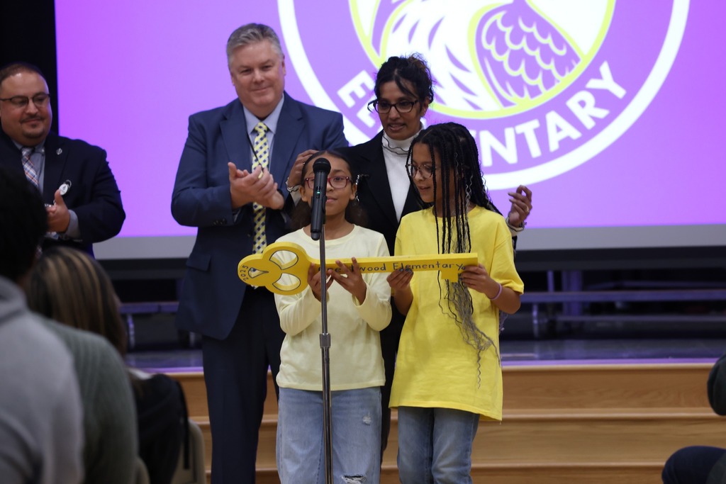 Two CWE students holding dedication key and speaking at mic