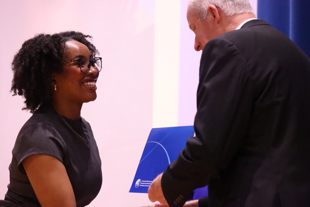 Student shaking hands and receiving diploma and medal.