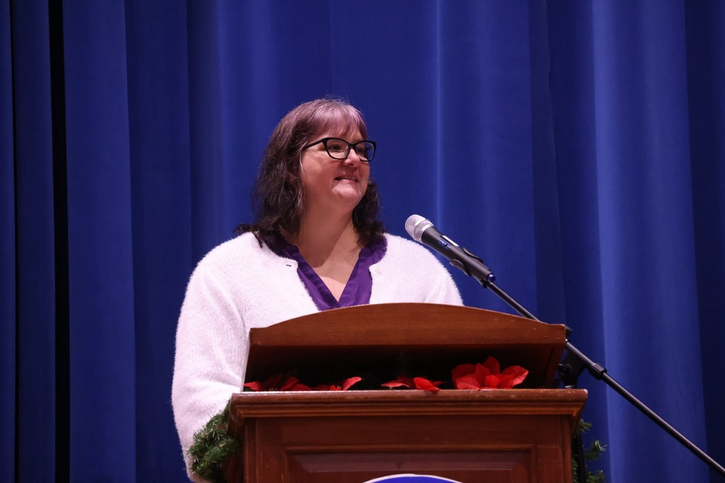 Teacher, IB coordinator,speaking at the podium.