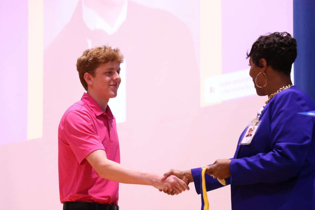 Student shaking hands and receiving diploma and medal.