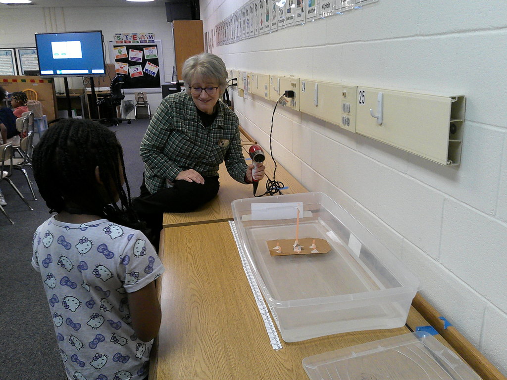 Mrs. Whitten and one of her student engineers watch her boat move, powered by the "wind" of a hair dryer