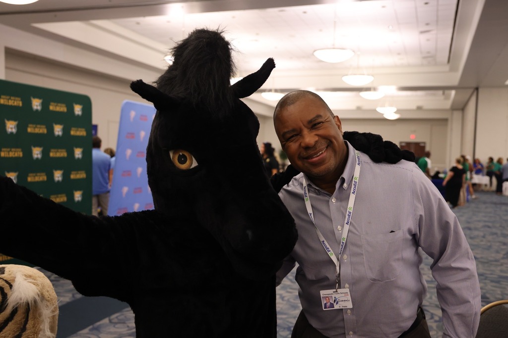 male middle school principal smiling with mustang mascot