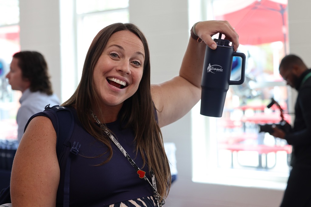 female middle schoolprnicipal holding up mug and smiling
