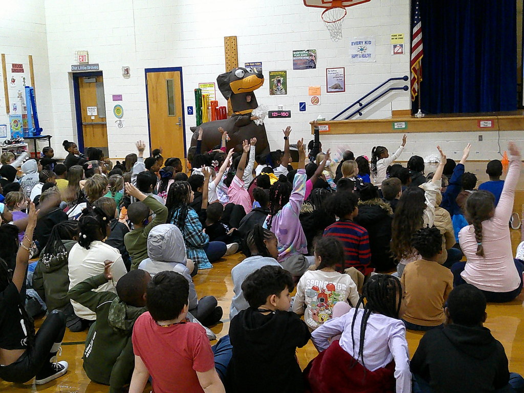 students participating at PBIS Pep Rally - hands raised to answer the question and spin the wheel