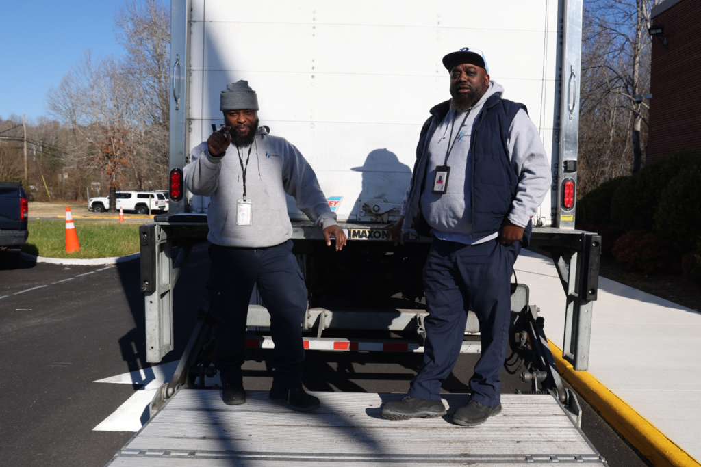 Ron and Emanuel smiling on back of white truck