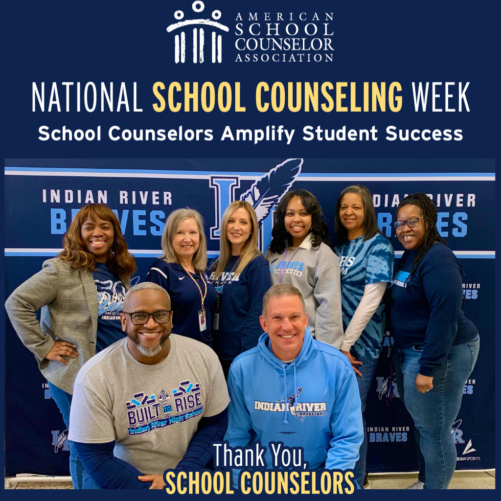 A group photo of the Indian River High School counseling team, consisting of eight members (six women and two men) smiling in front of a blue "Indian River Braves" backdrop. At the top, the American School Counselor Association logo is displayed above the text "NATIONAL SCHOOL COUNSELING WEEK: School Counselors Amplify Student Success." Two men are kneeling in the front; one wears a grey shirt that says "Built to Rise," and the other wears a light blue Indian River hoodie. The six women stand behind them wearing various blue and grey Indian River apparel. At the bottom, the text reads, "Thank You, School Counselors."