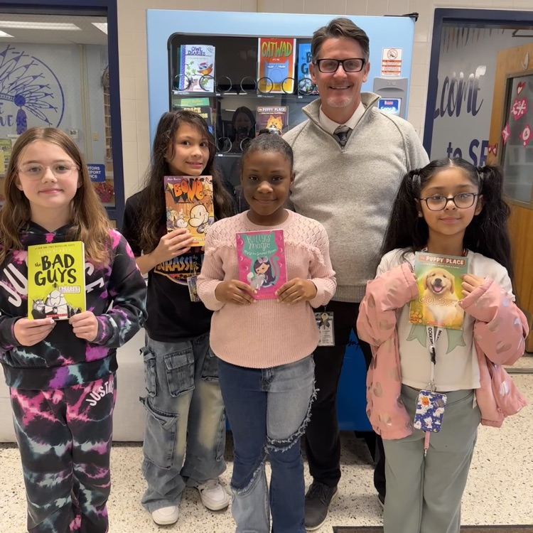Students for honesty with books with Mr. Triolet in front of the book machine.
