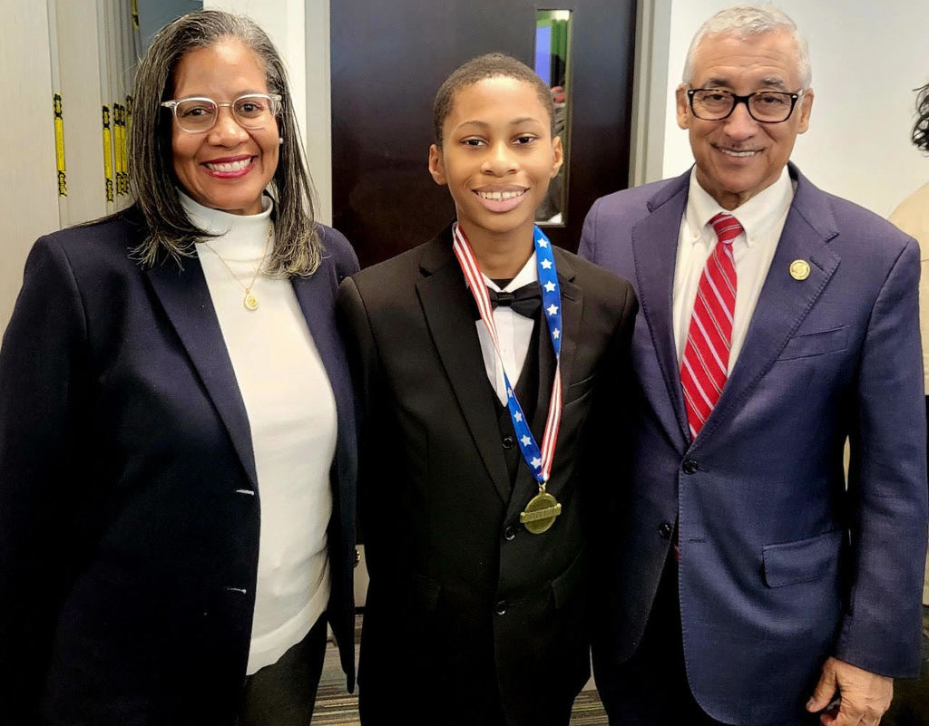 Bobby Scott, student and female adult smiling with medal.