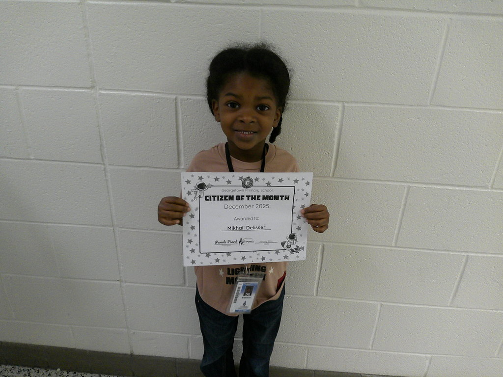 Mikhail Delisser holding his Citizen of the Month certificate