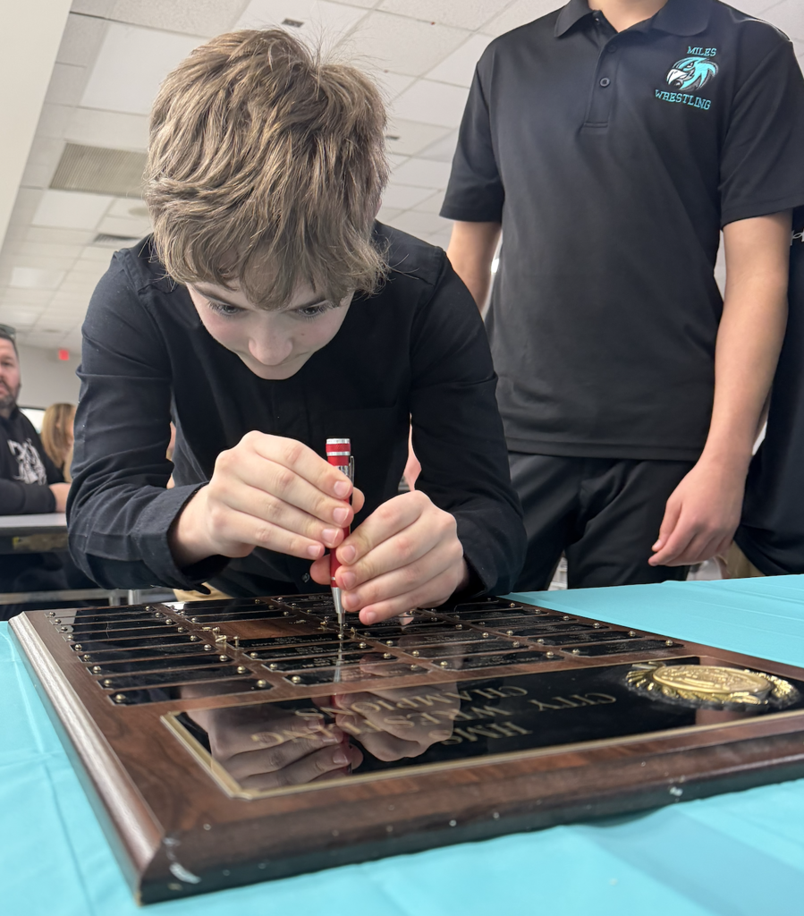student fixing his name plate to the plaque