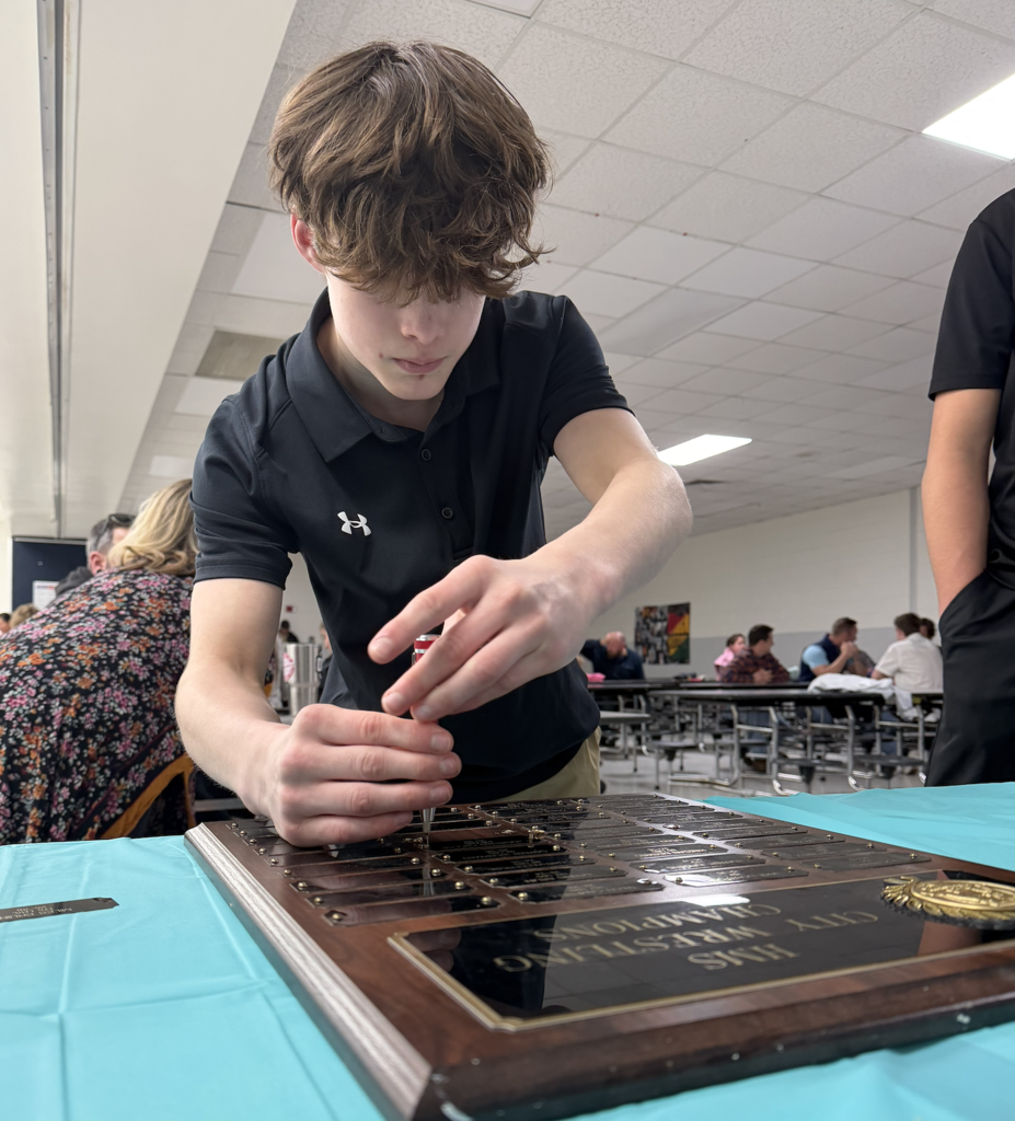student fixing his name plate to the plaque