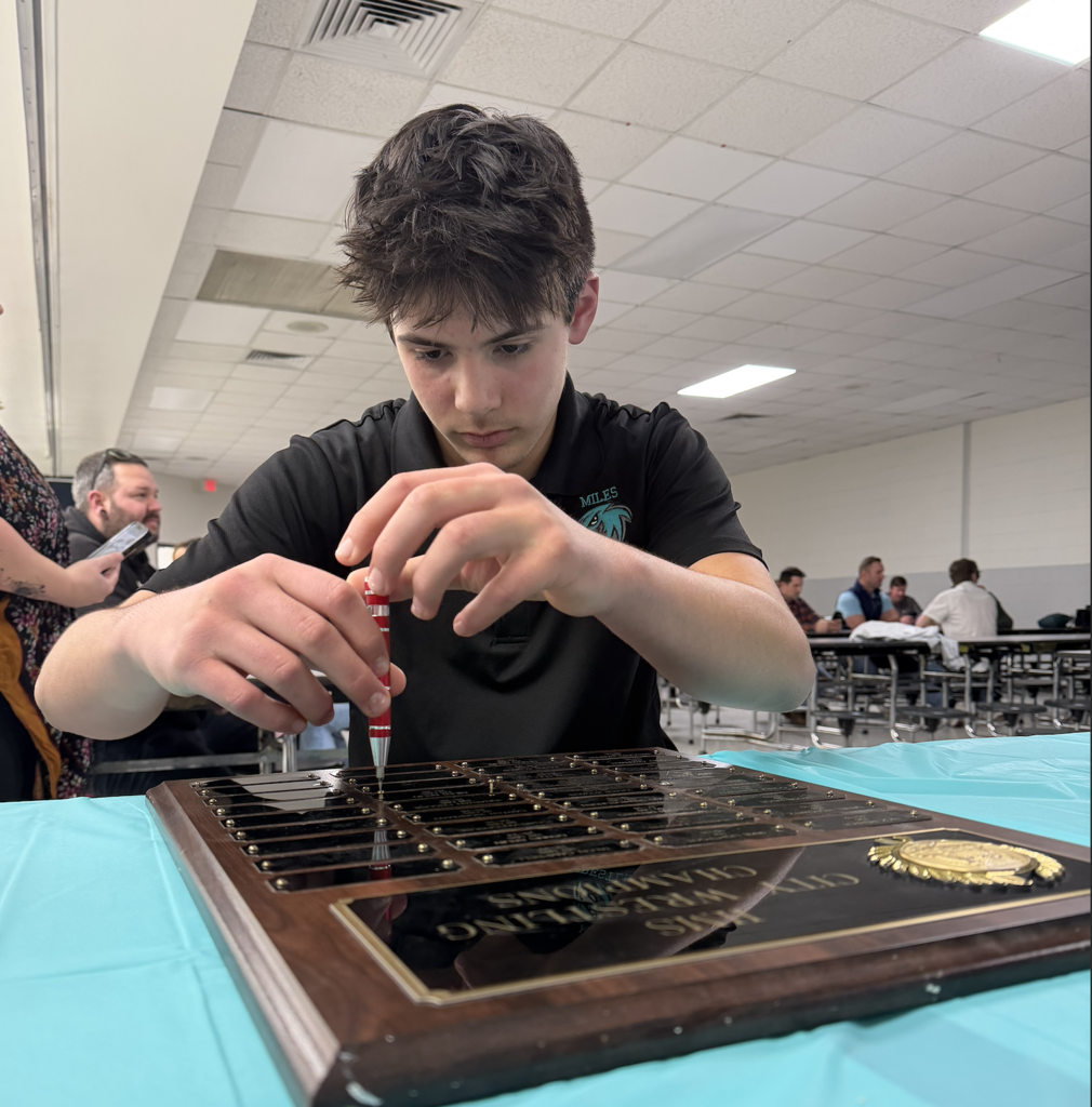 student fixing his name plate to the plaque