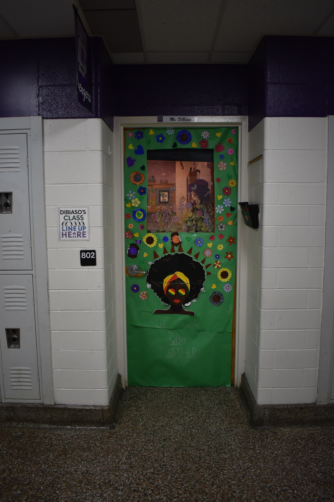 A green door decorate for Black History Month. It has a woman with flowers around her.