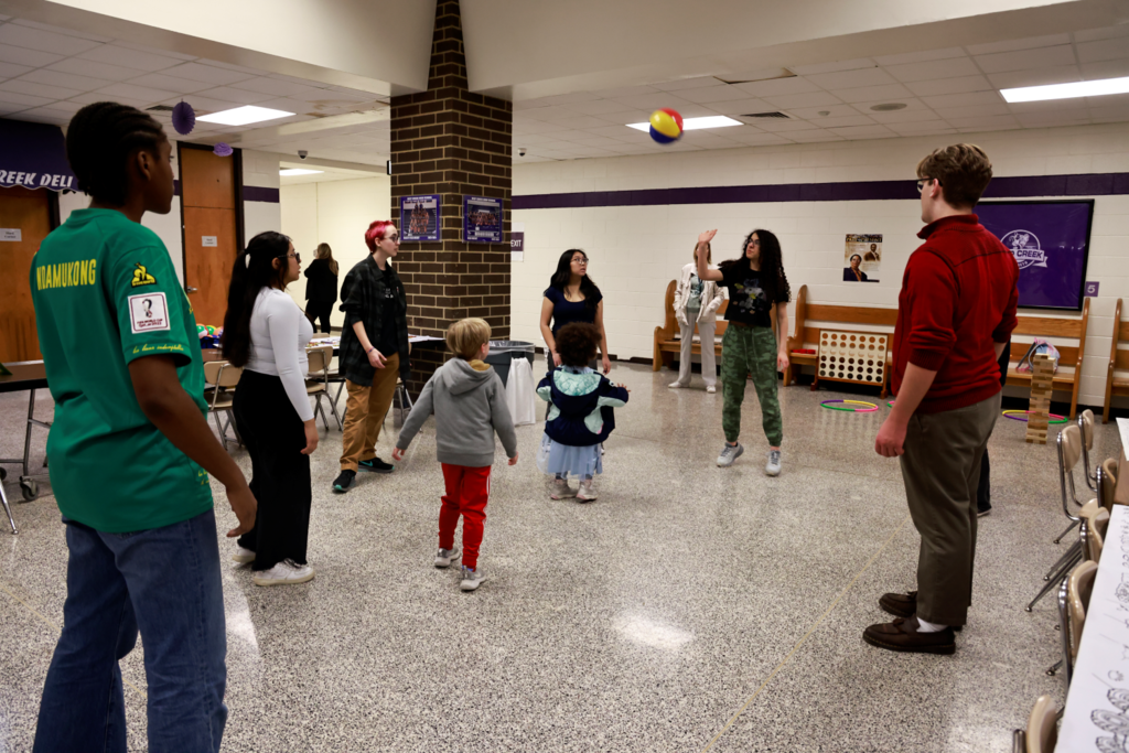 Group of teens and little kids playing with a beach ball in cafeteria