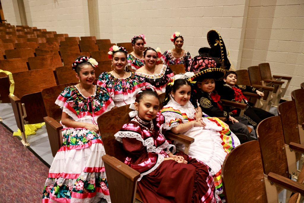 Group of adult and child flamenco dancers smiling for camera