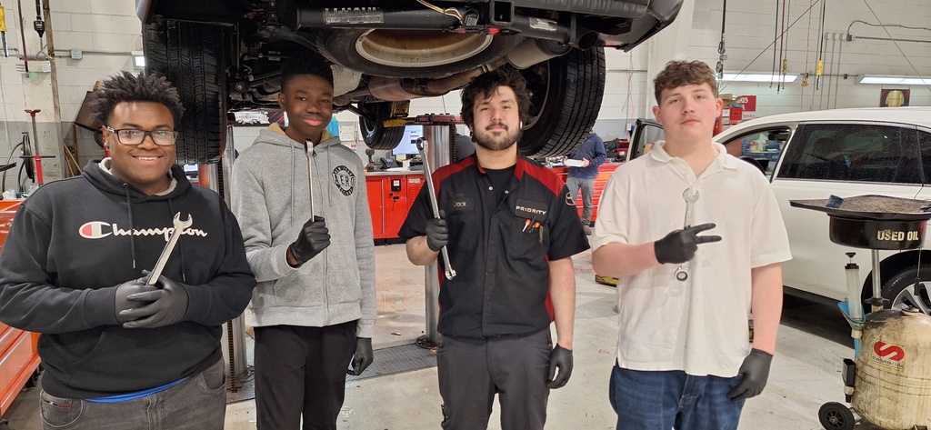 students and mentor holding up car tools