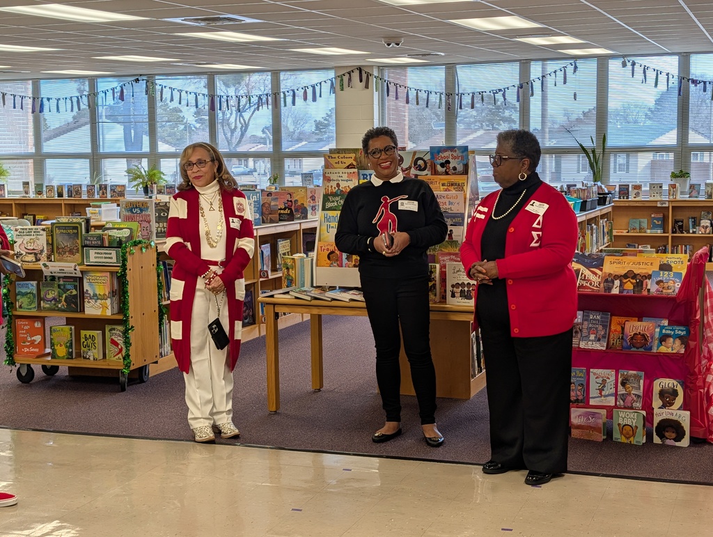 3 ladies speaking in front of donated books