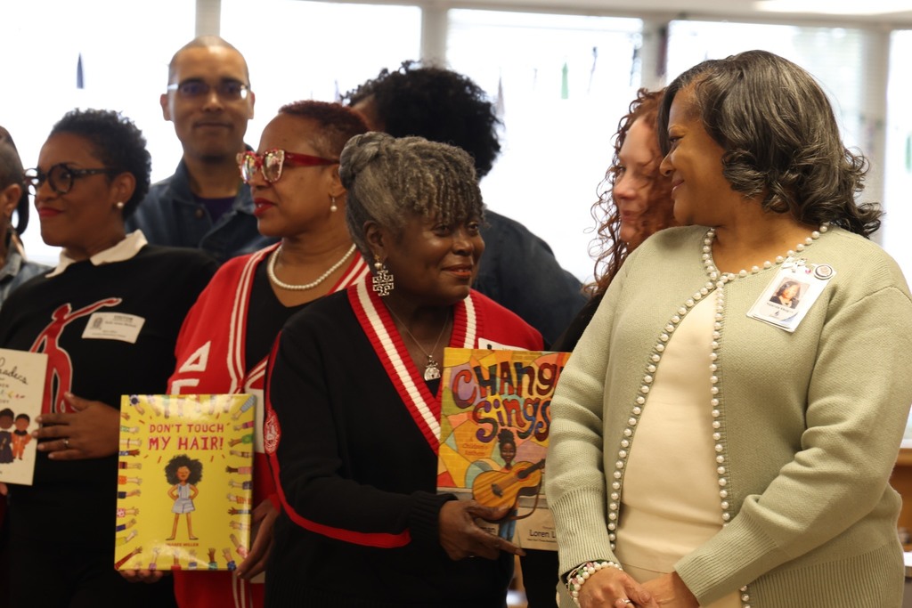 CPS employee and sorority sister smiling with book
