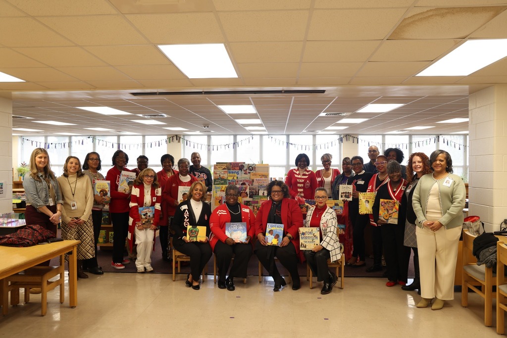 group shot of sorority sisters and cps employees in library holding books